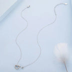 Full white gold-plated sterling silver necklace laid out with its open heart infinity pendant