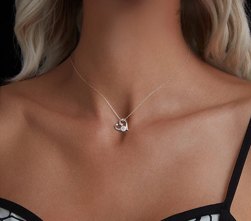 Sterling silver open heart necklace worn at the collarbone, showing the bright round moissanite