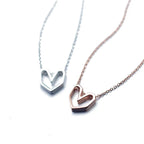 Geometric heart necklaces in silver-tone and rose gold-tone 925 sterling silver with faceted open hearts on a white background