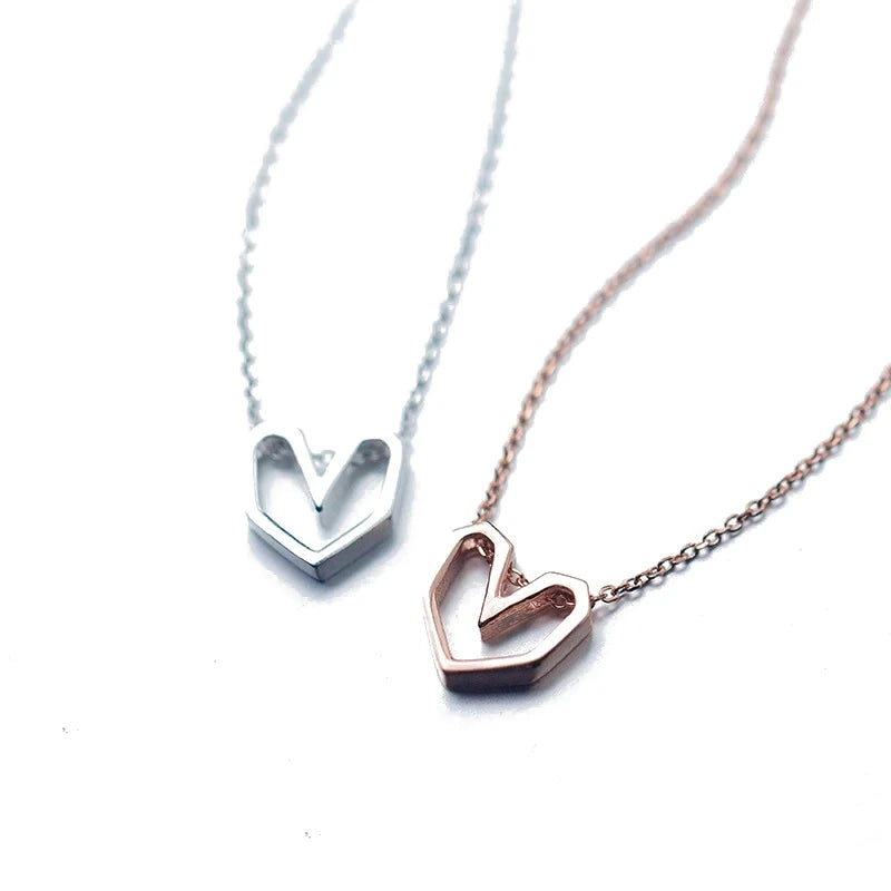 Geometric heart necklaces in silver-tone and rose gold-tone 925 sterling silver with faceted open hearts on a white background