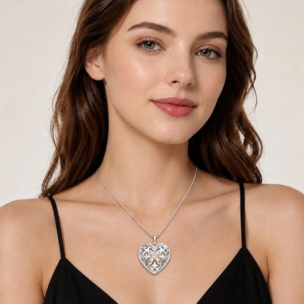 Woman wearing a sterling silver openwork heart locket on a fine box-link chain at the collarbone