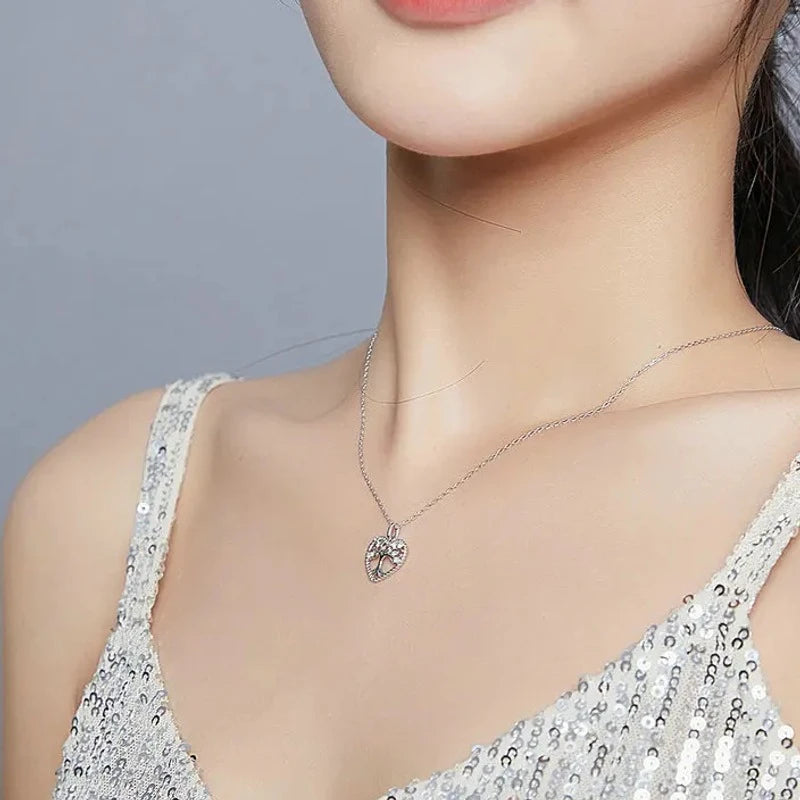 Openwork tree of life heart necklace worn below the collarbone with sparkling CZ stones along the branches