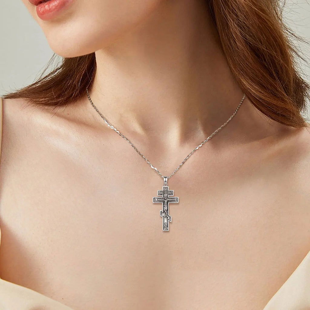 Silver Orthodox crucifix necklace worn on the neck, showing the three-bar cross silhouette