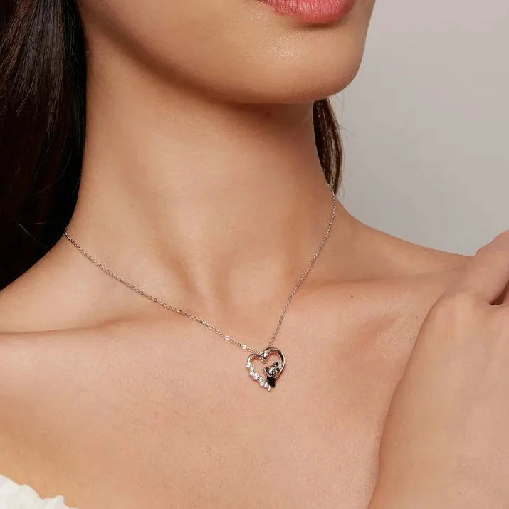 Silver-tone panda heart pendant necklace worn at the collarbone with black enamel details