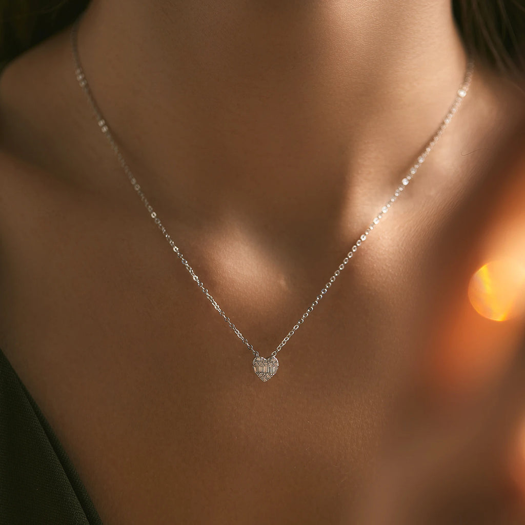 Small sterling silver pave heart necklace with clear CZ stones worn centered at the base of the neck