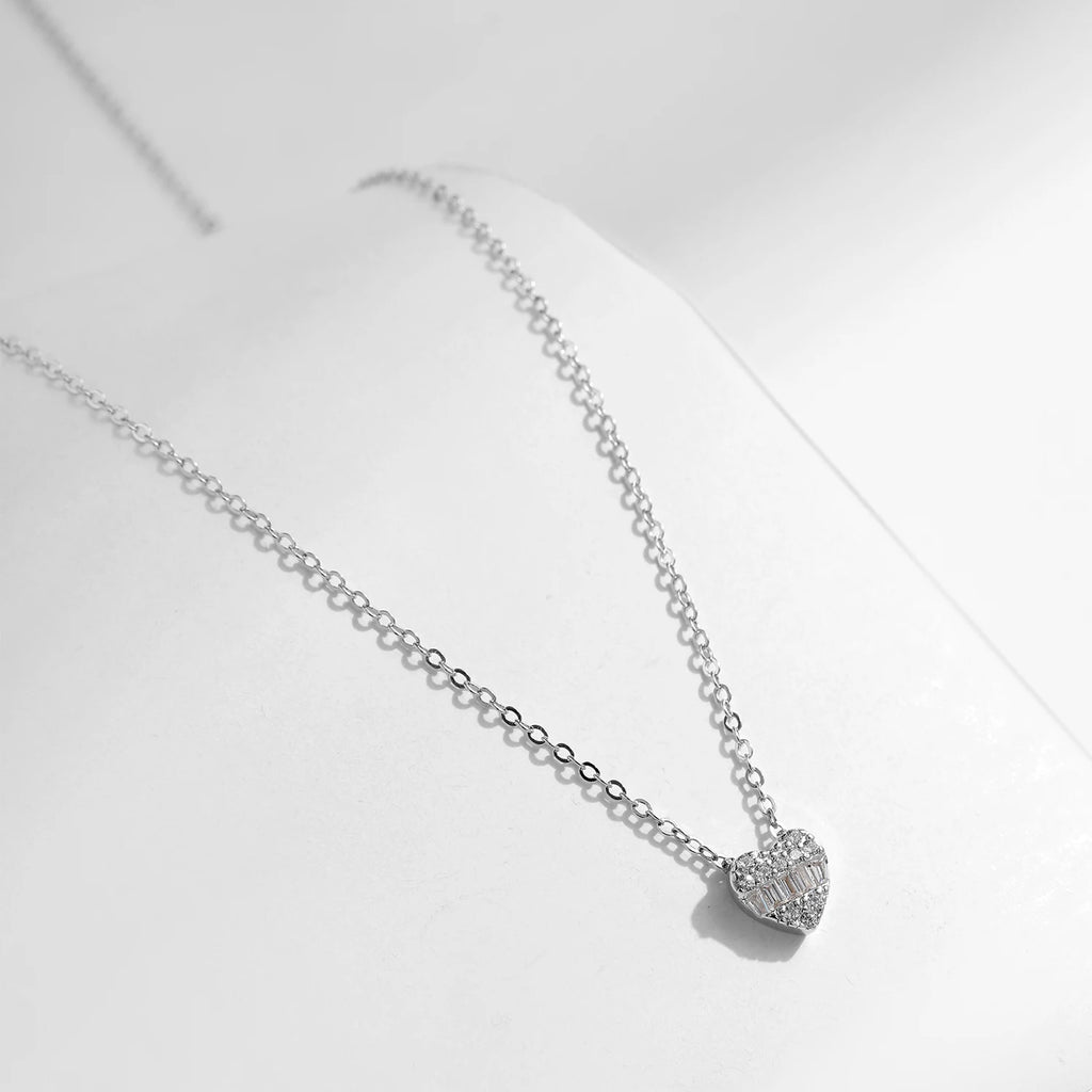 Angled view of a small pave heart pendant with a horizontal row of rectangular clear stones