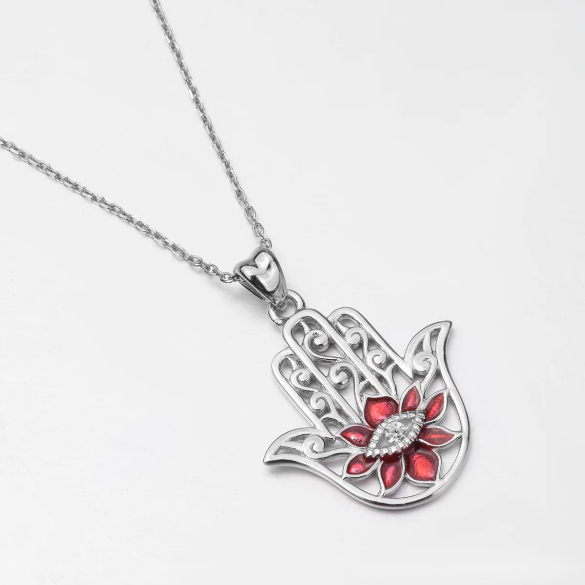 Red flower hamsa necklace on a white background with openwork fingers and a clear stone eye