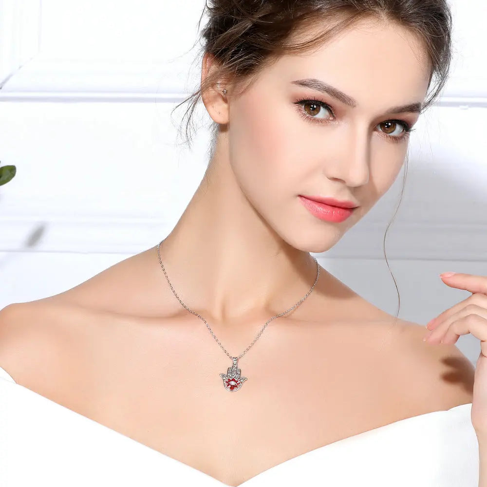 Red flower hamsa necklace worn at the collarbone on an oval-link chain