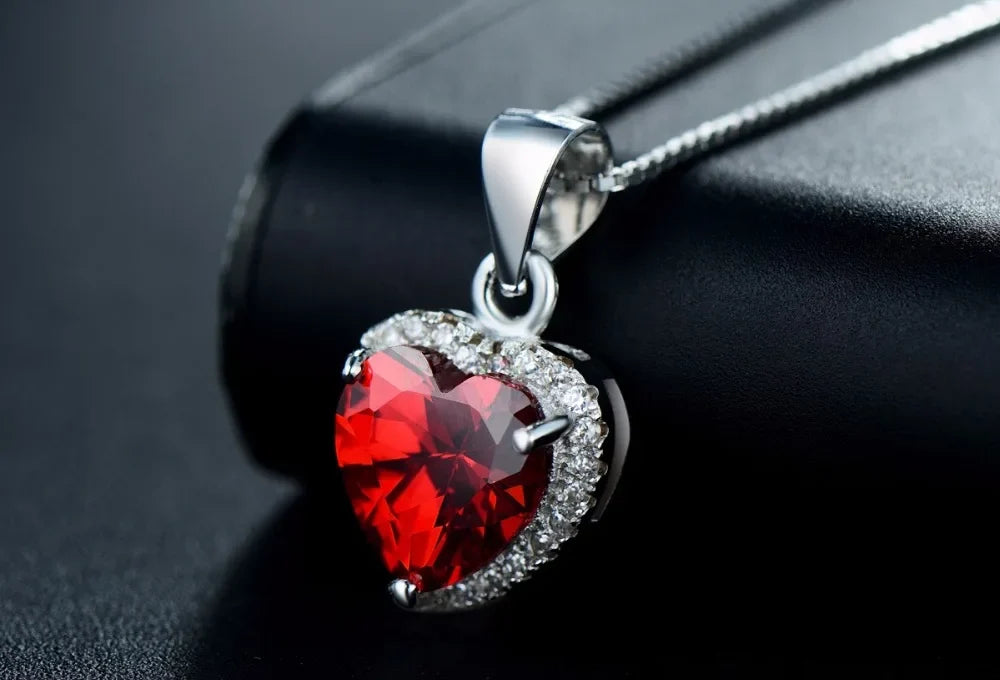 Angled close-up of the red heart CZ pendant framed by small clear CZ stones on a box chain