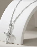 Silver-tone woven Celtic cross necklace on a white curved stand with a round clear center stone