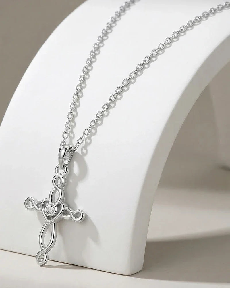 Silver-tone woven Celtic cross necklace on a white curved stand with a round clear center stone