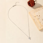 Silver-tone cross necklace flat lay showing the oval-link chain, clasp, and stone-filled pendant