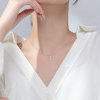 Silver-tone necklace worn with a stone-set cross centered below heart and star charms
