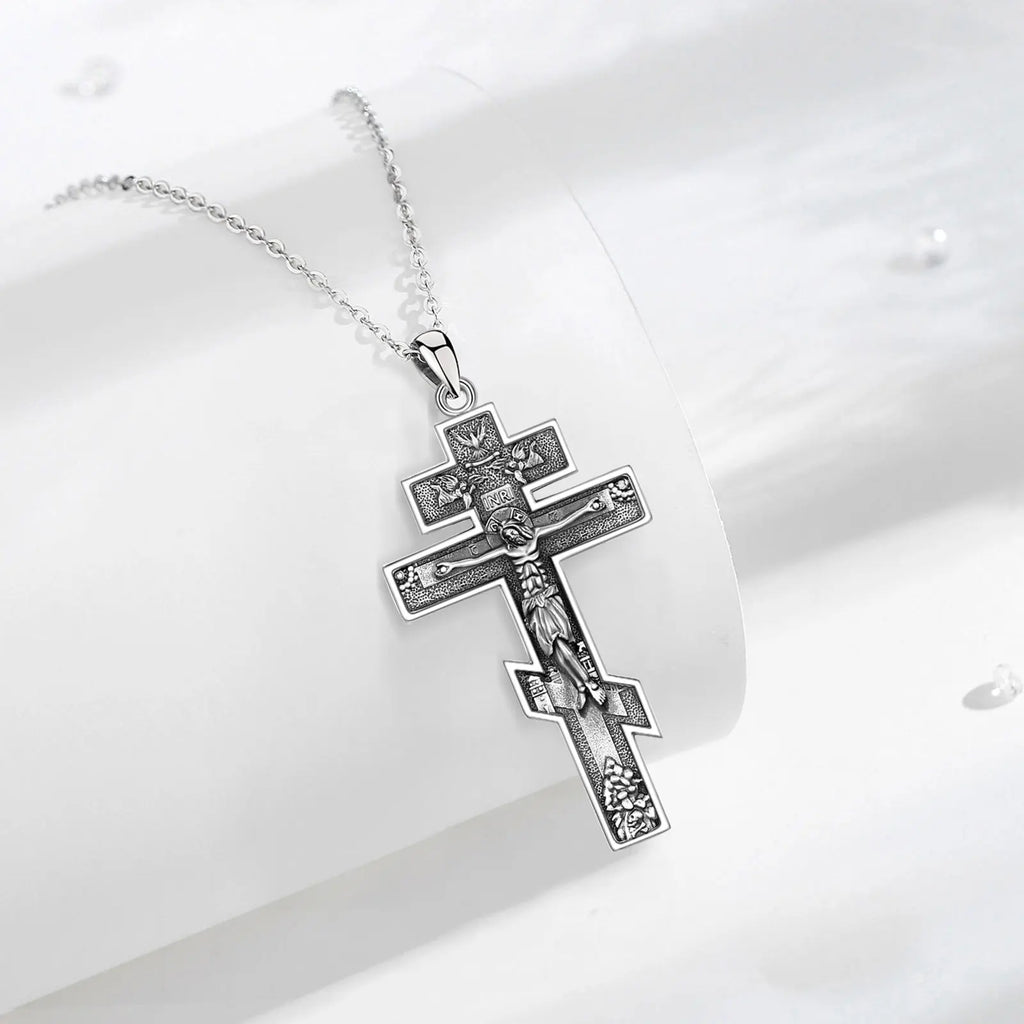 925 sterling silver crucifix necklace displayed on a white curved surface with darkened relief details