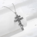 925 sterling silver crucifix necklace displayed on a white curved surface with darkened relief details