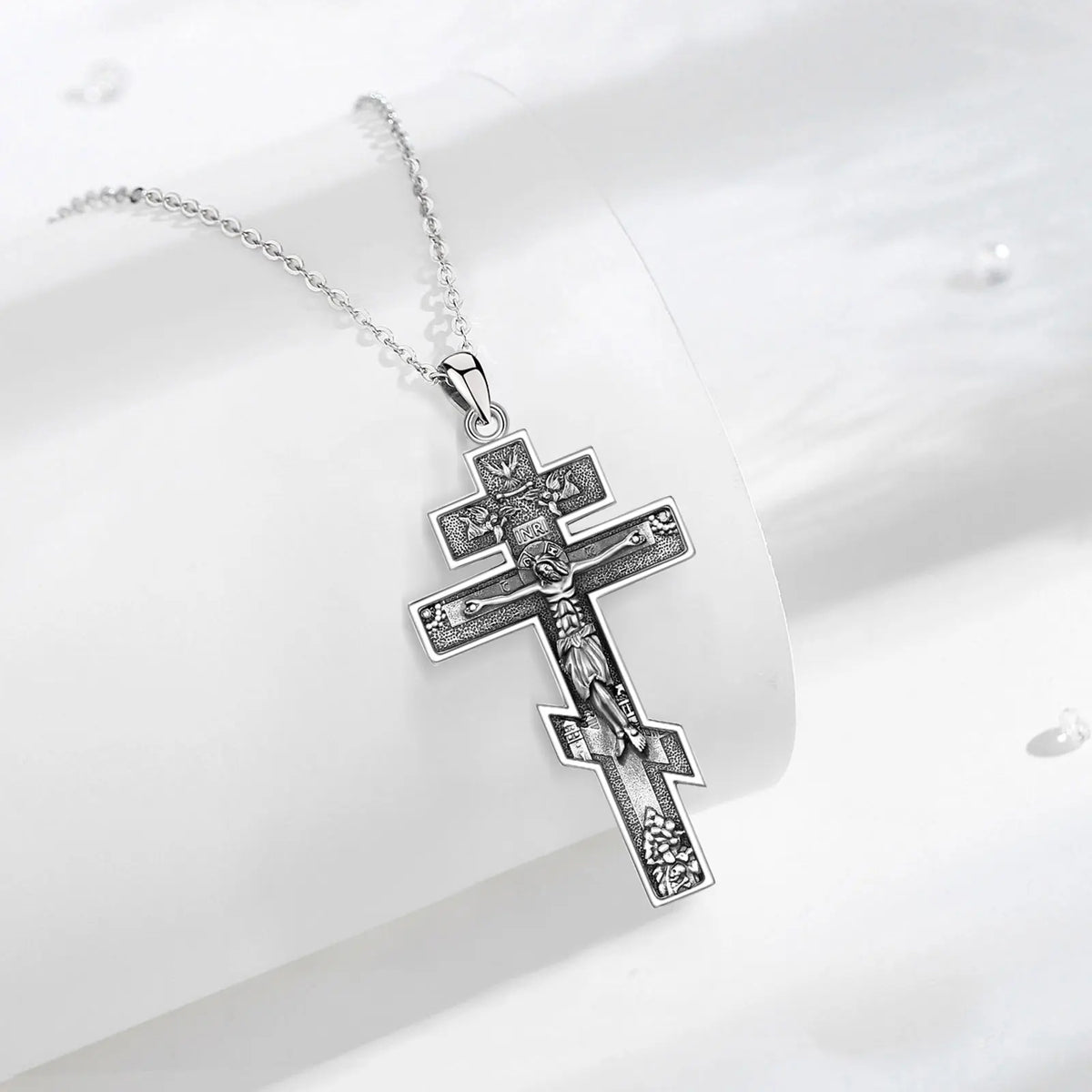 925 sterling silver crucifix necklace displayed on a white curved surface with darkened relief details
