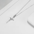 Silver-tone crucifix necklace laid beside a white dish with the textured figure of Christ in view