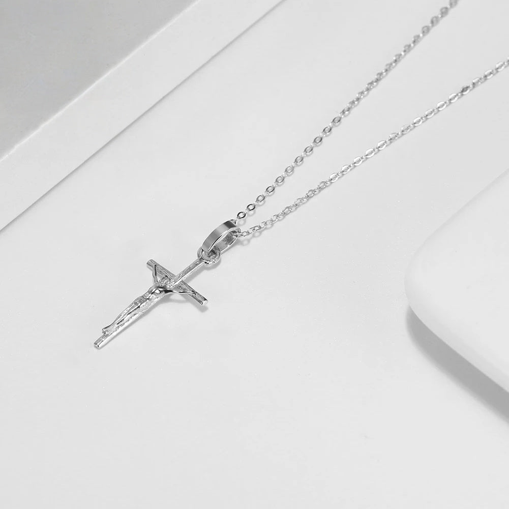 Silver-tone crucifix necklace laid beside a white dish with the textured figure of Christ in view