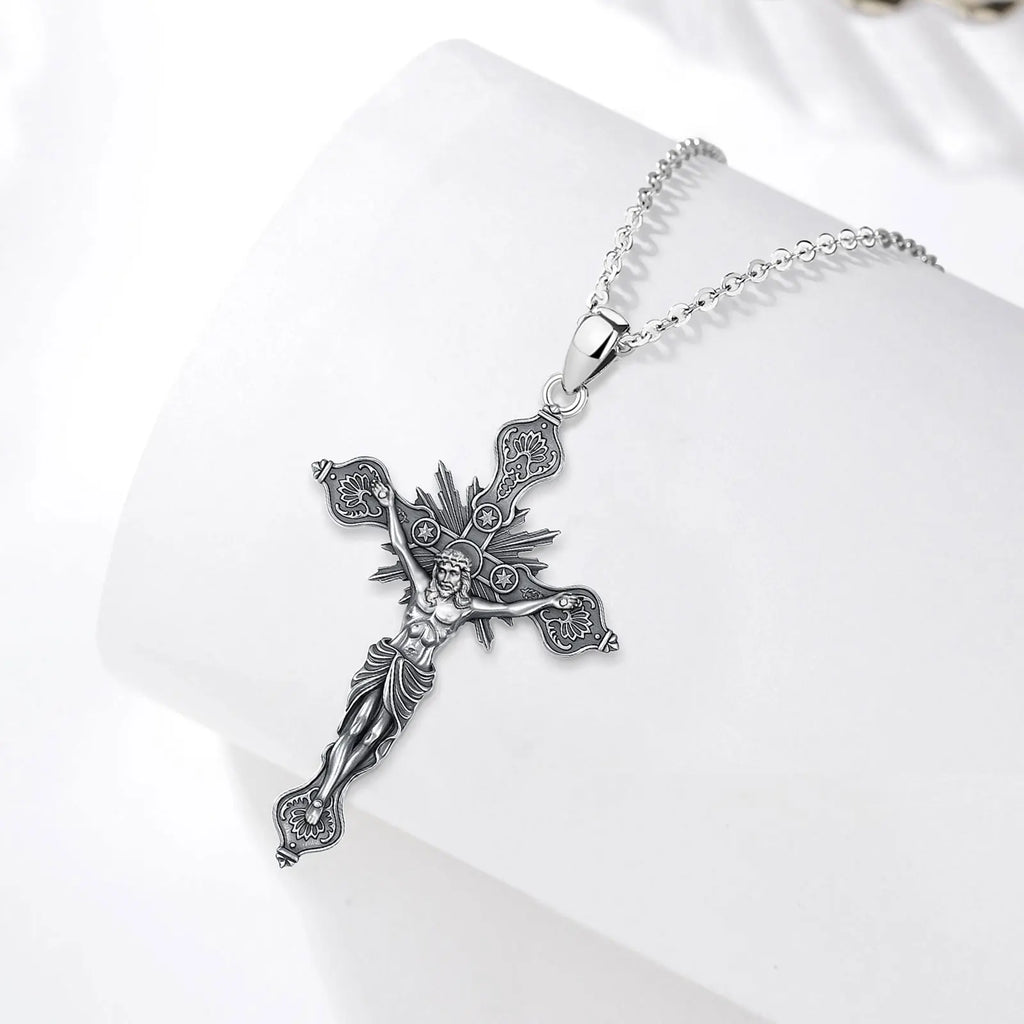 Sterling silver crucifix necklace displayed on a white curved surface with radiating rays and star circles