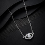Silver-tone evil eye necklace on black textured fabric with clear stone-set outline