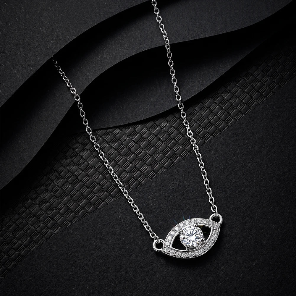 Silver-tone evil eye necklace on black textured fabric with clear stone-set outline