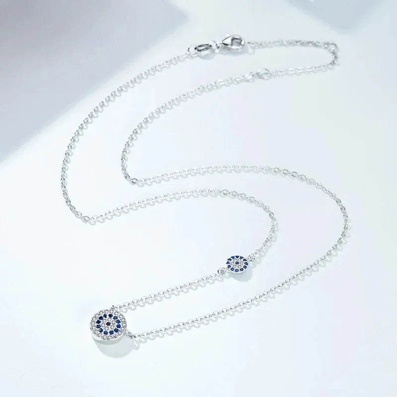 Silver-tone evil eye necklace arranged in loops, showing the clasp and two blue cubic zirconia medallions