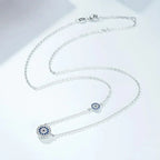 Silver-tone evil eye necklace arranged in loops, showing the clasp and two blue cubic zirconia medallions