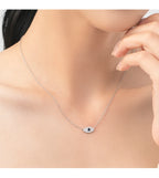 Silver-tone sideways evil eye necklace worn high on the neck with a blue center stone