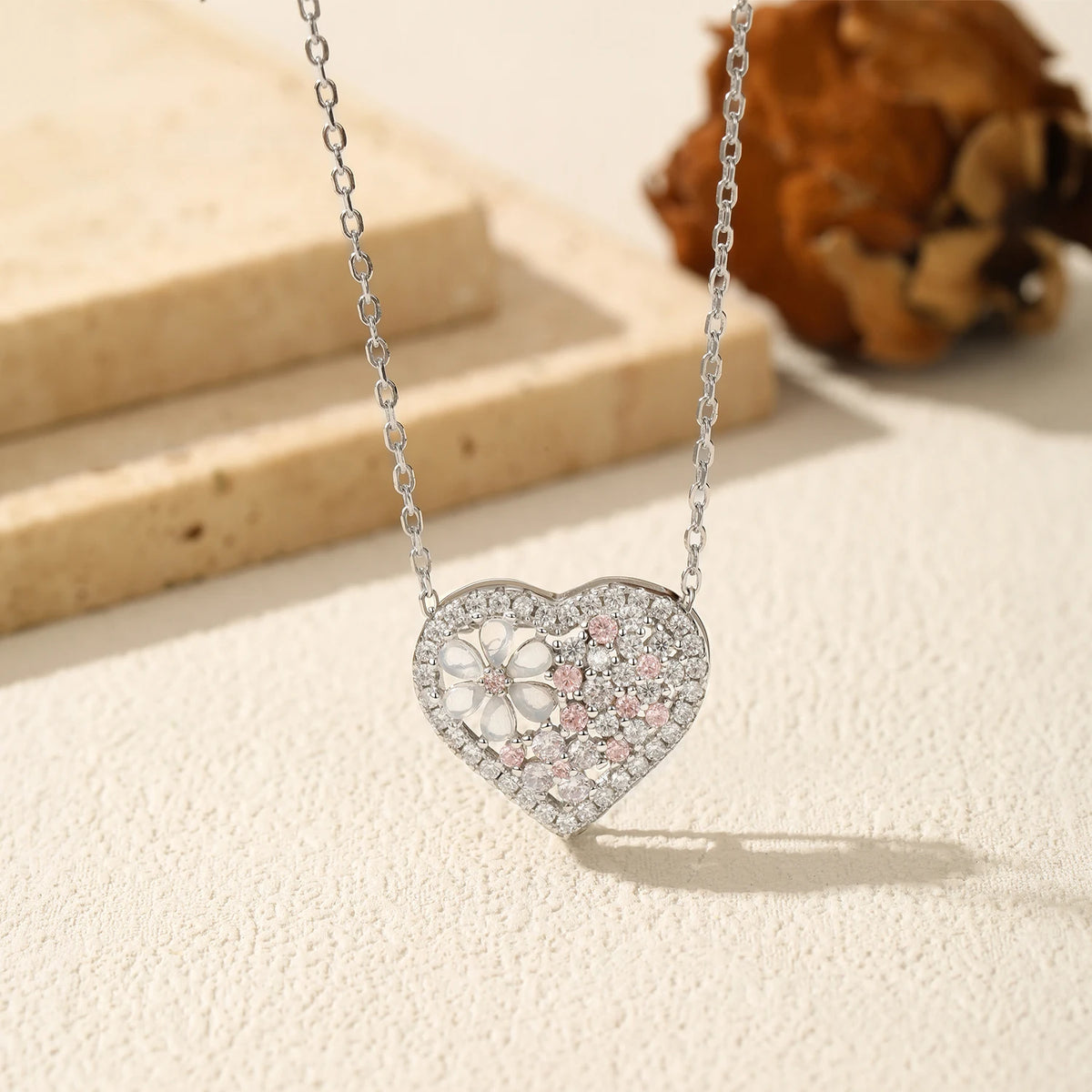 Close-up of the sterling silver heart pendant with a translucent flower, clear CZ stones, and pale pink accents