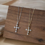 Sparkling silver cross necklaces with clear stones displayed on a wood block