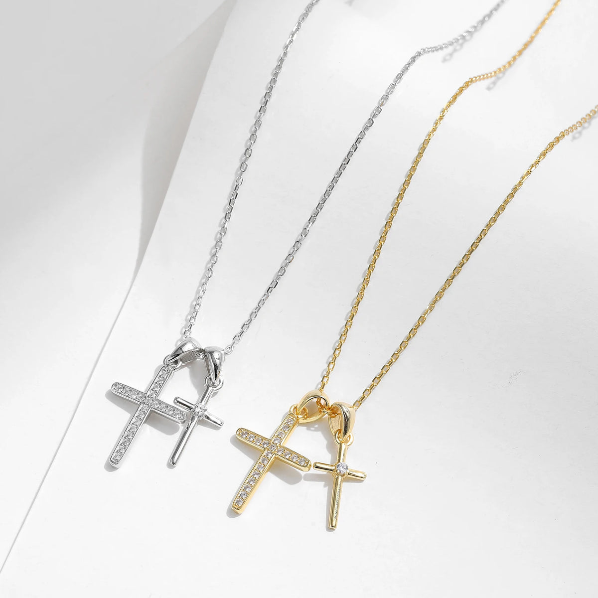 Silver-tone and gold-tone necklaces displayed flat with overlapping polished and CZ-set crosses