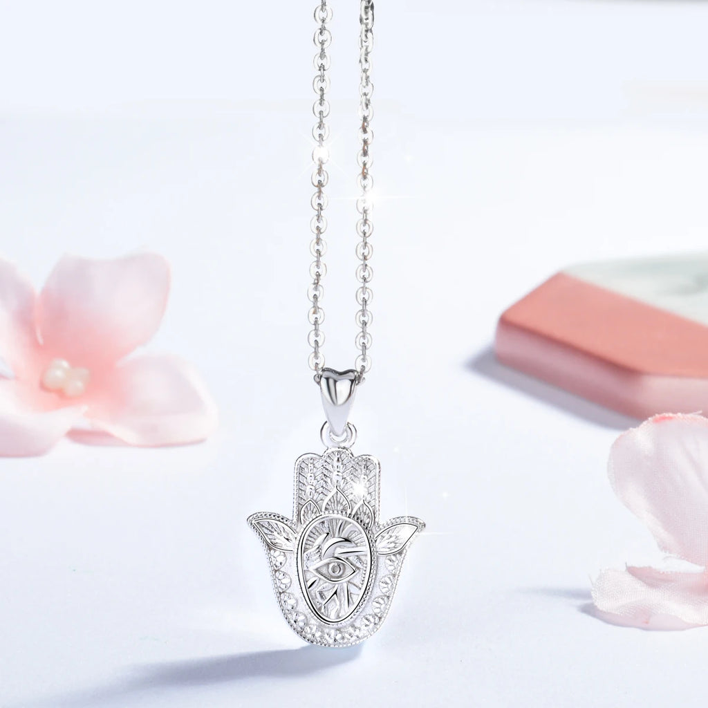 925 sterling silver hamsa necklace hanging against a white background with floral props