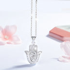 925 sterling silver hamsa necklace hanging against a white background with floral props