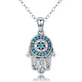 Silver-tone hamsa necklace close-up with blue CZ stones, a six-pointed star, and openwork scroll fingers