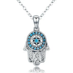 Silver-tone hamsa necklace close-up with blue CZ stones, a six-pointed star, and openwork scroll fingers