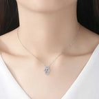 Silver-tone hamsa hand necklace worn at the collarbone with a clear stone border and center stone