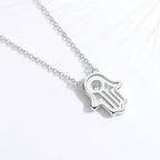 Back view of a silver-tone hamsa pendant necklace showing the open palm design and round center stone