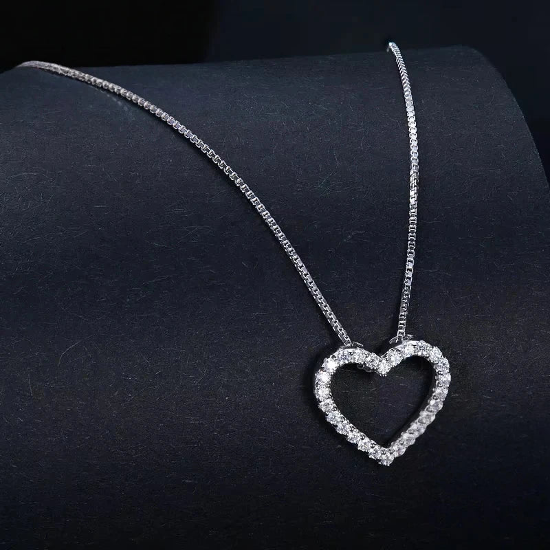 Silver 925 sterling silver heart necklace with a moissanite-paved open heart on a dark surface