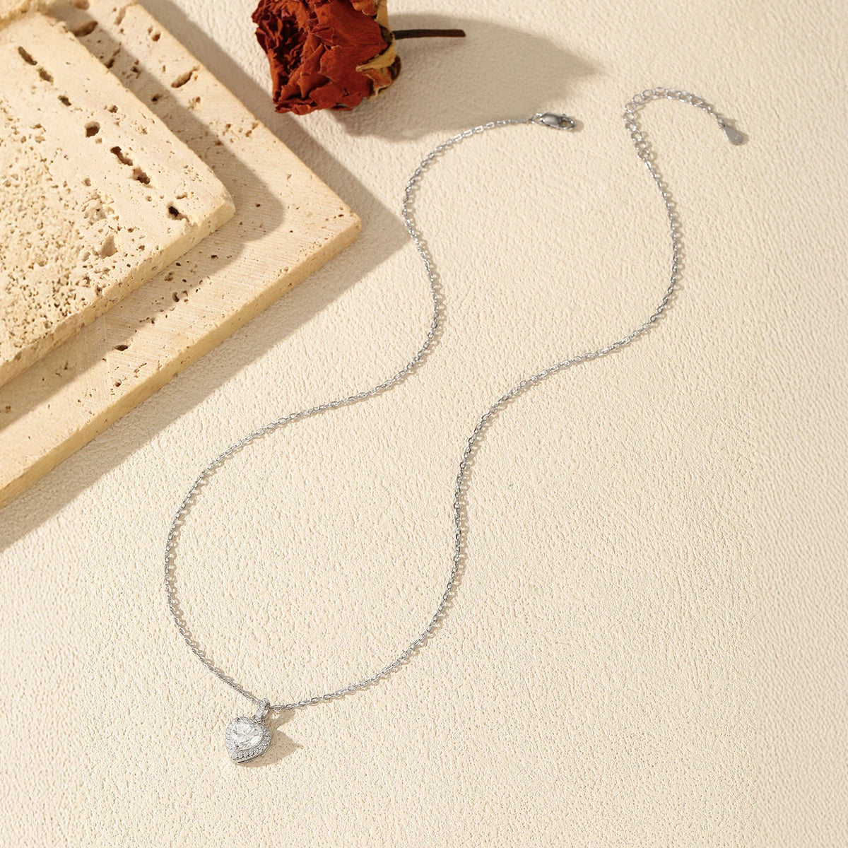 Full silver necklace flat lay with a halo heart pendant, oval-link chain, and clasp