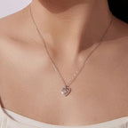 Silver nested heart pendant necklace worn at the collarbone, showing the stone-lined outer heart and center moissanite