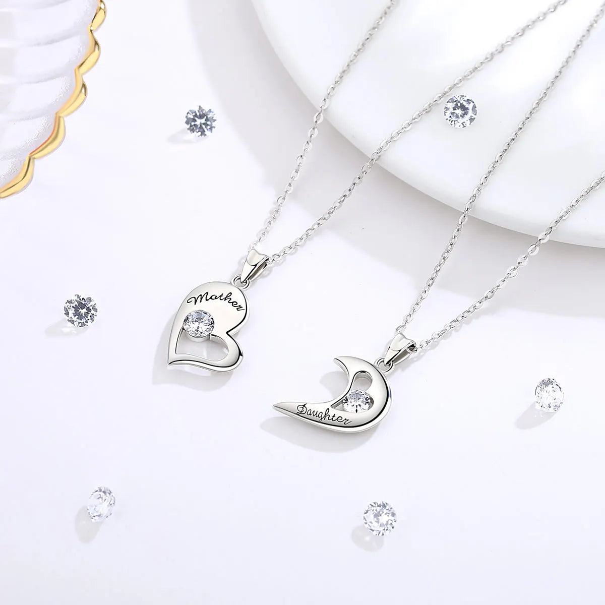 Silver-tone Mother heart and Daughter crescent necklaces with clear crystal stones on white props