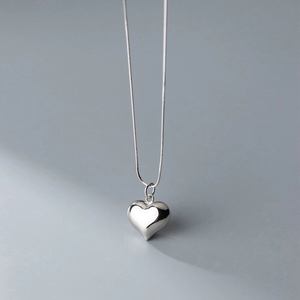 Silver-tone heart necklace with a rounded reflective pendant and small connector ring
