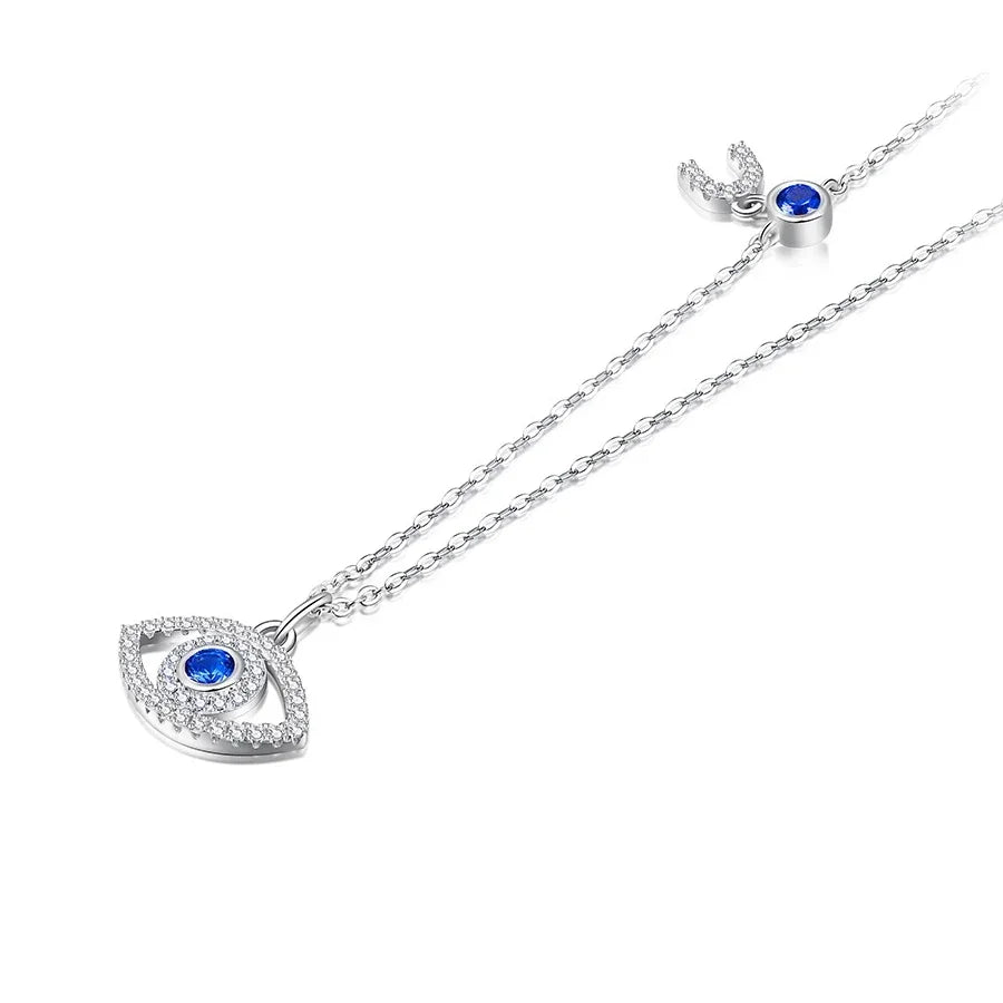 Silver-tone evil eye necklace with blue CZ stones, a clear stone outline, and crescent chain detail on white