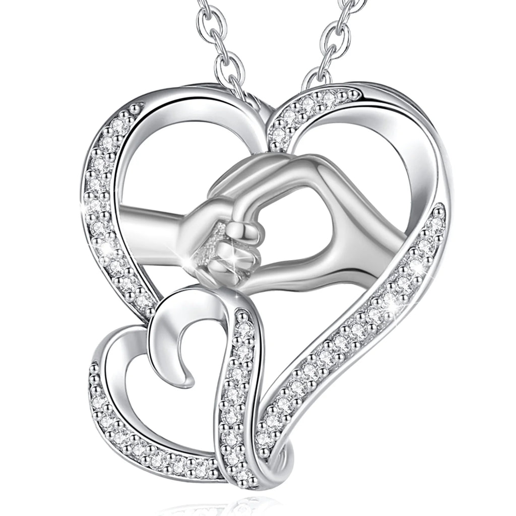 Silver-tone hand in hand heart necklace with clear CZ accents and a silver-colored chain on white