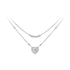 Silver-tone layered heart necklace with polished bead strands and a clear stone-bordered heart on white