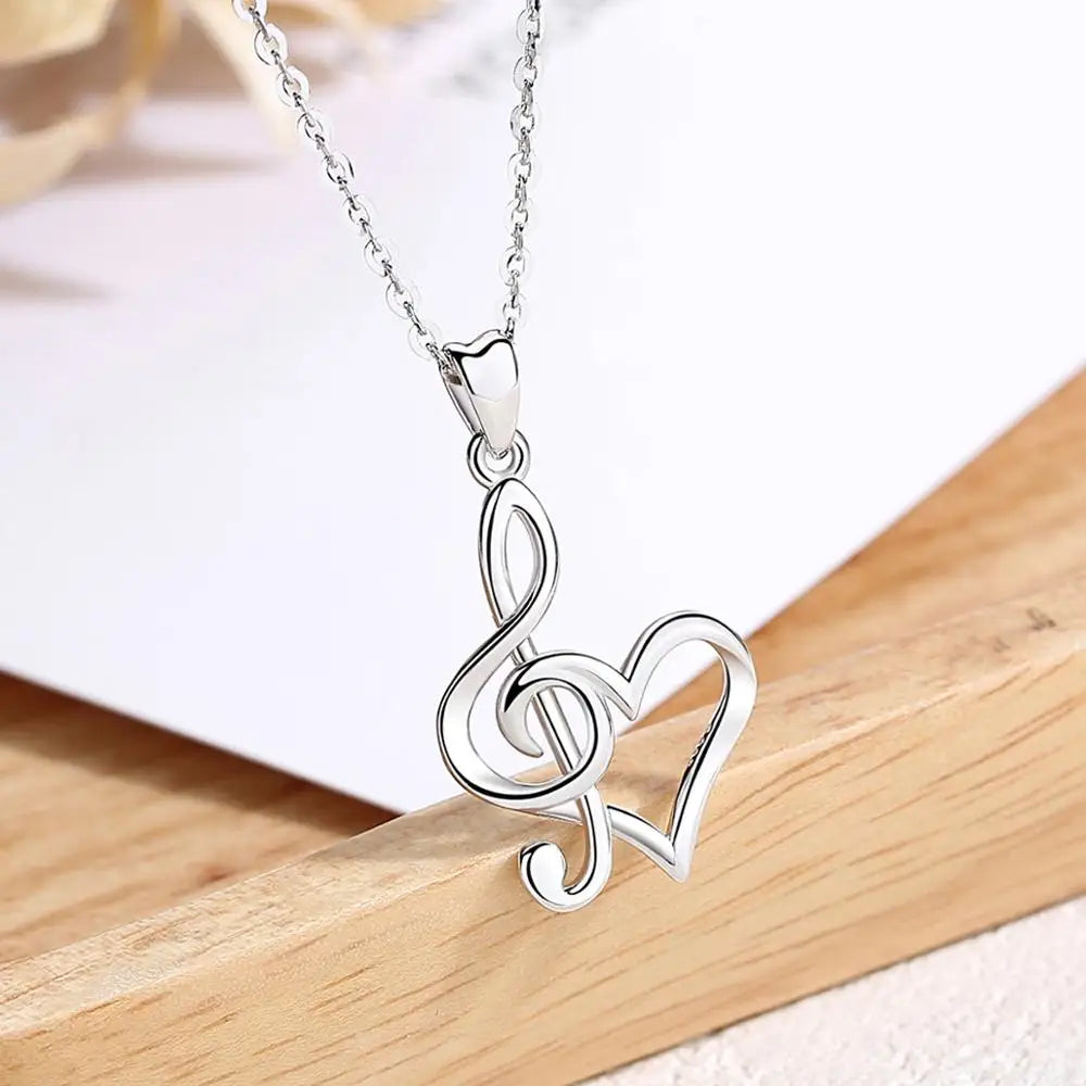 Polished 925 sterling silver treble clef and heart pendant hanging over a wood surface