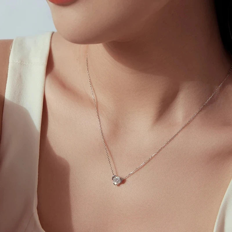 Small moissanite heart pendant on a silver-tone chain worn with a white top