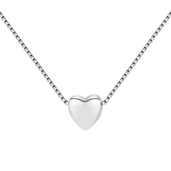 Close-up of the small polished silver heart pendant sliding on a fine box-link chain