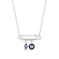 Sterling silver evil eye necklace with a horizontal safety pin, blue Hamsa charm, and round eye on white