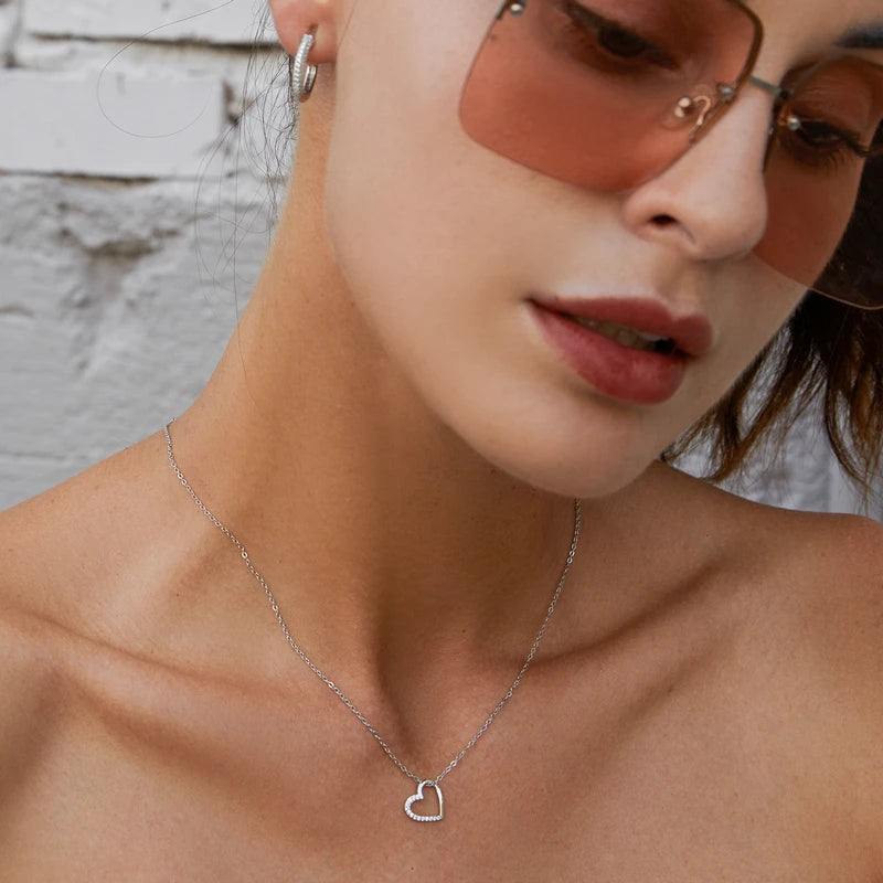 925 sterling silver open heart pendant worn on the neck, showing its off-center outline and CZ stone edge